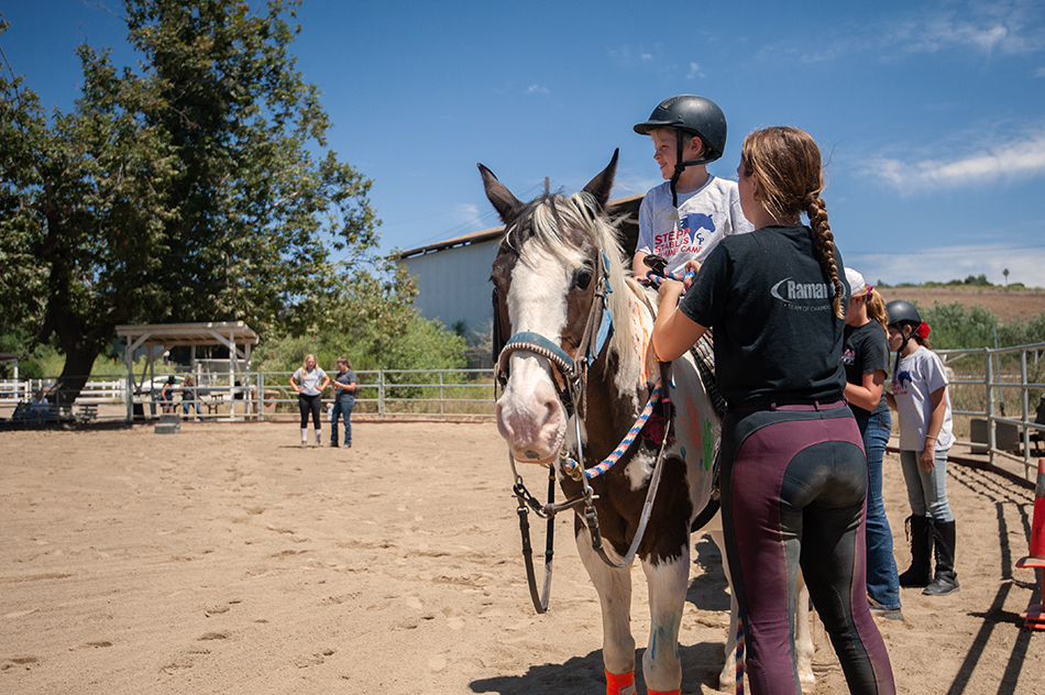 stepp-stables_summer-camp-counselor-fixes-childs-reins.jpg